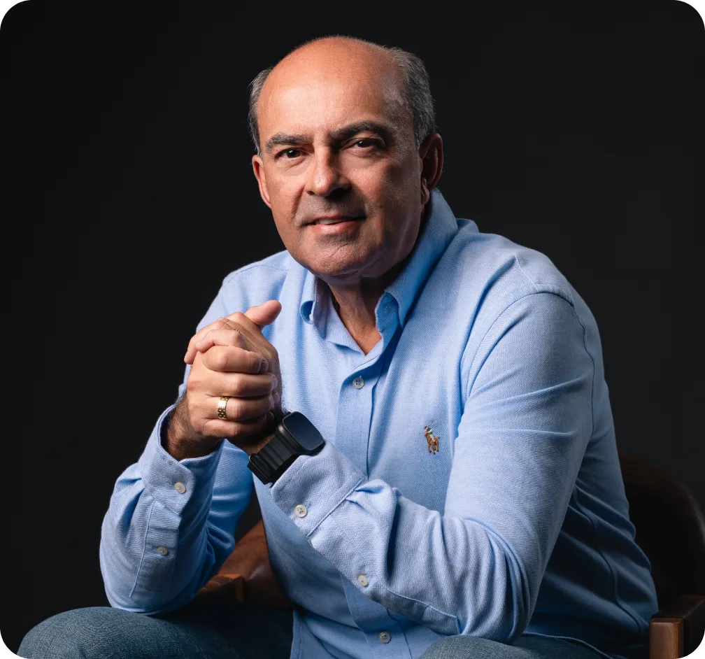 Poty Ferraz sentado, de camisa azul, sorrindo para a câmera